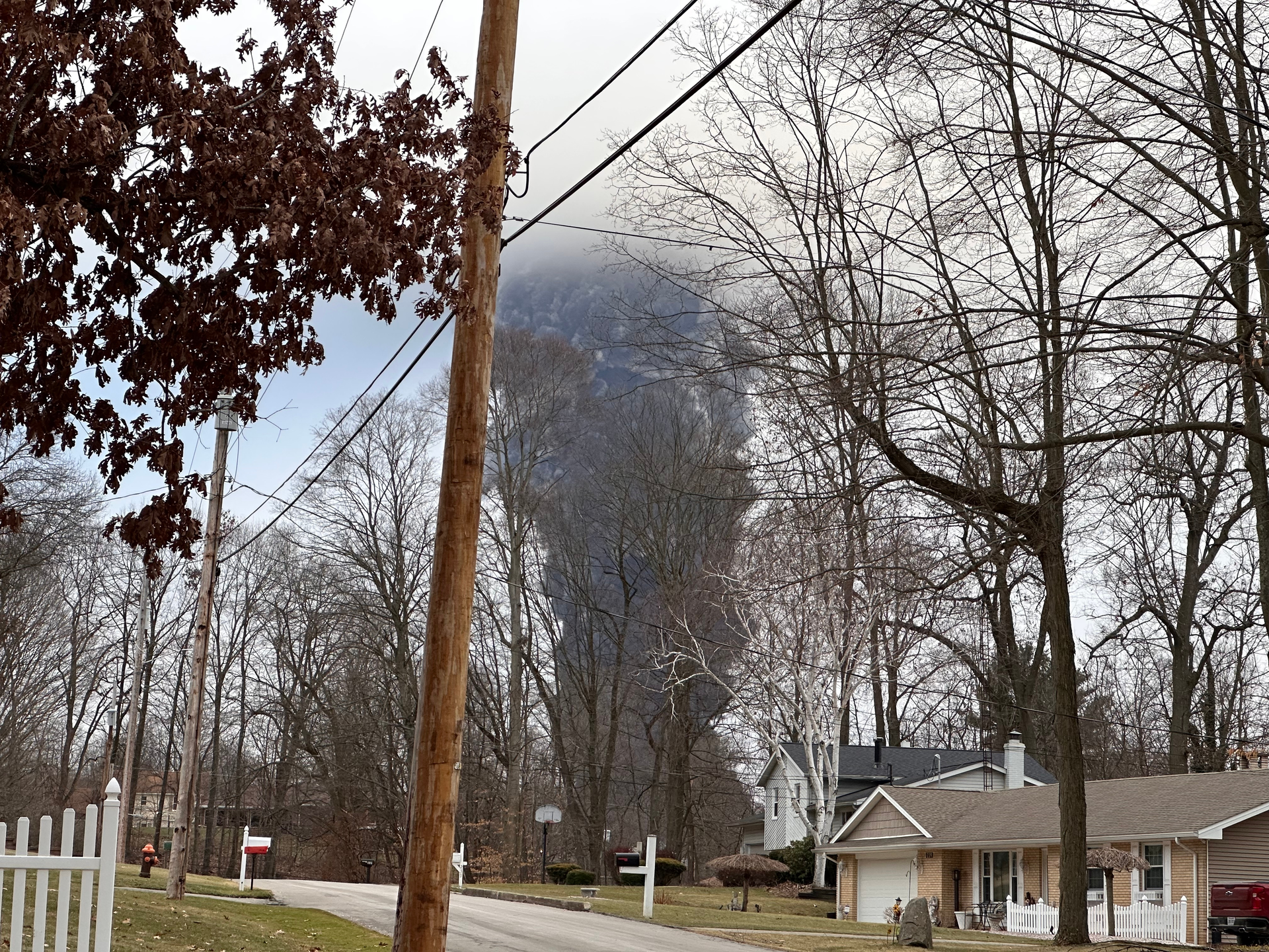 The rising smoke cloud after authorities released chemicals from a train derailment as seen from the ground in a nearby neighborhood.