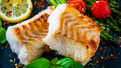 Fish dish - fried cod fillet with asparagus on wooden table Fish dish - fried cod fillet with asparagus on wooden table