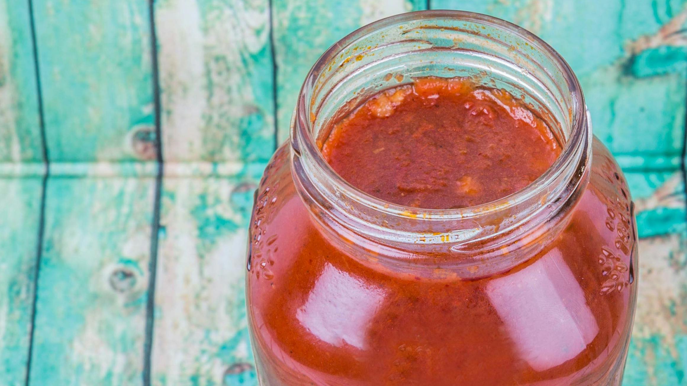 Spaghetti sauce in a glass jar over wooden background