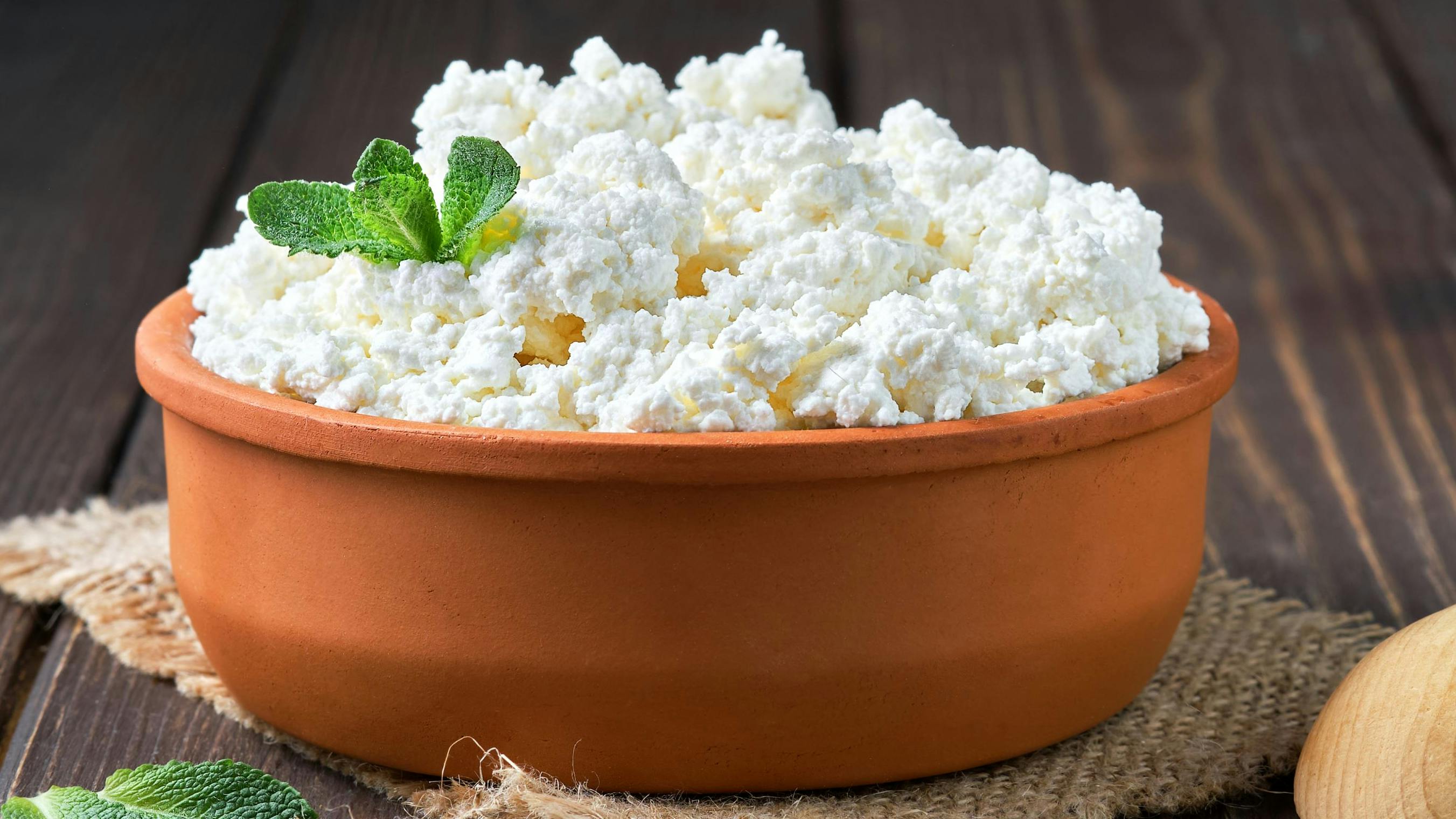 Farmer's Cottage Cheese In A Traditional Clay Bowl, Next To A Wooden Spoon, A Dark Wooden Background