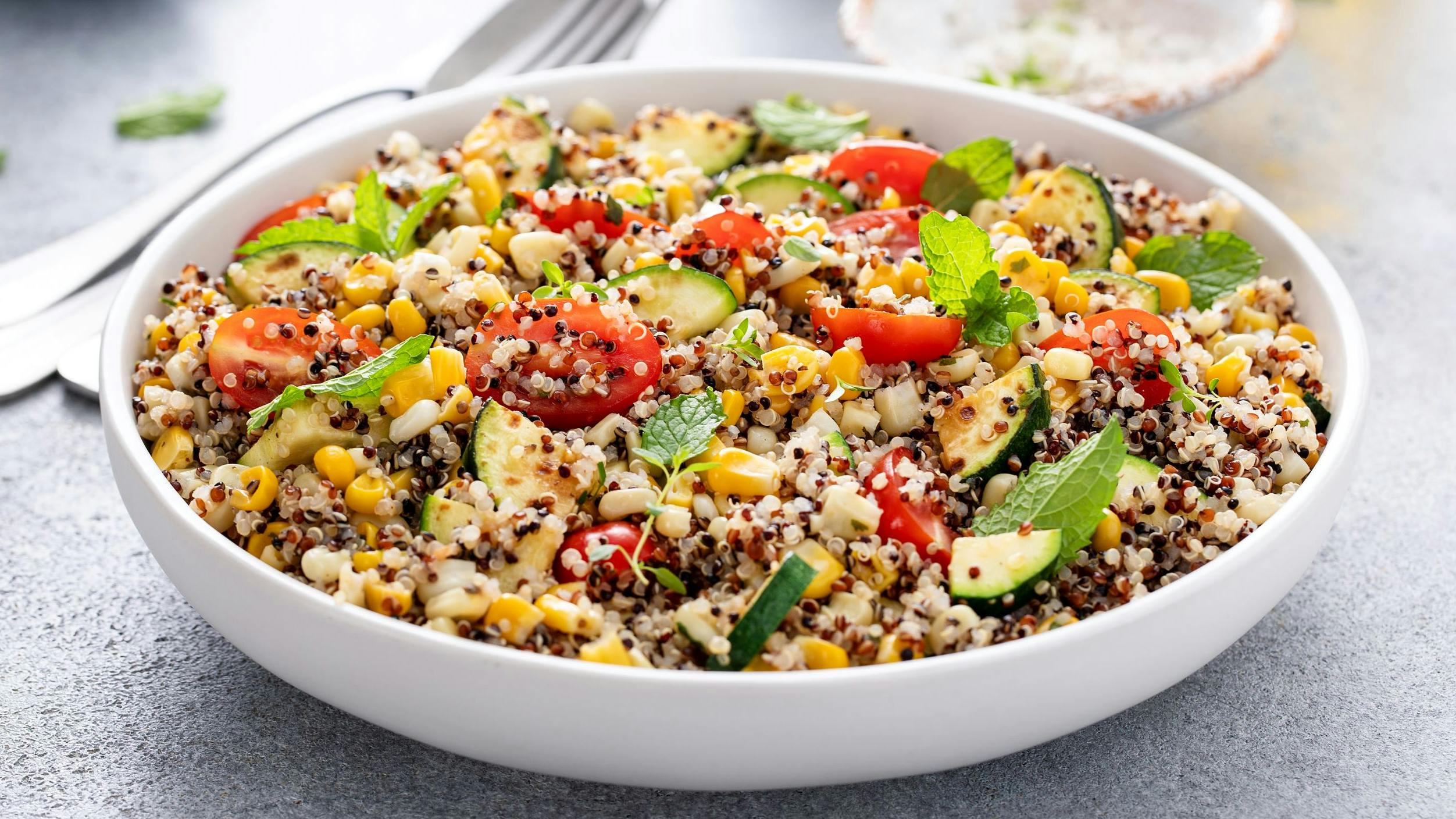 Warm quinoa salad with tomatoes, corn and zucchini with fresh mint and herbs