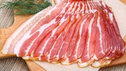 Fresh cold sliced bacon with dill branch on the wood background Fresh cold sliced bacon with dill branch on the wood background