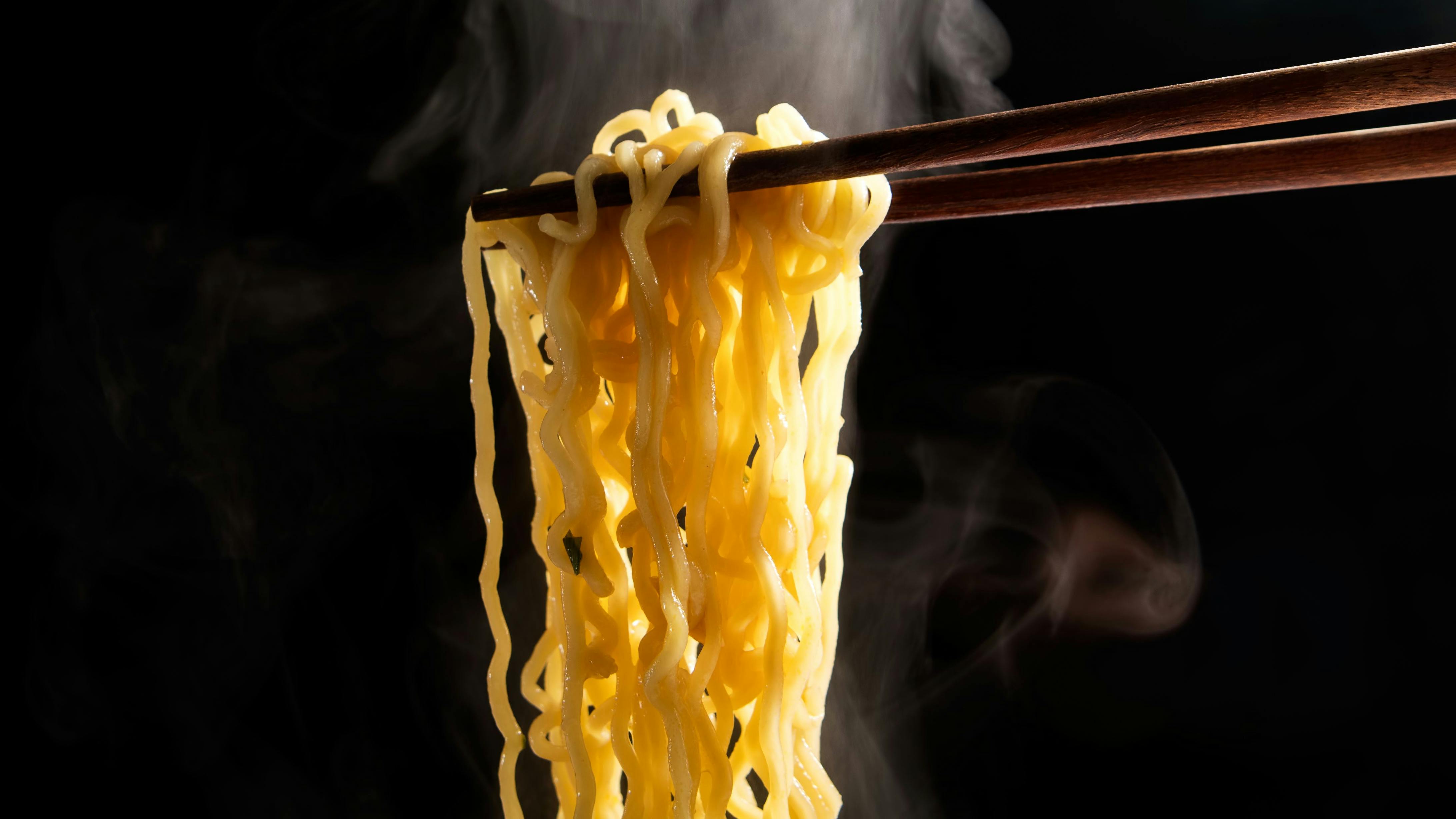 Lift With Wood Chopsticks And Fork To Pickup Noodle With Steam And Smoke Isolated On Black Background
