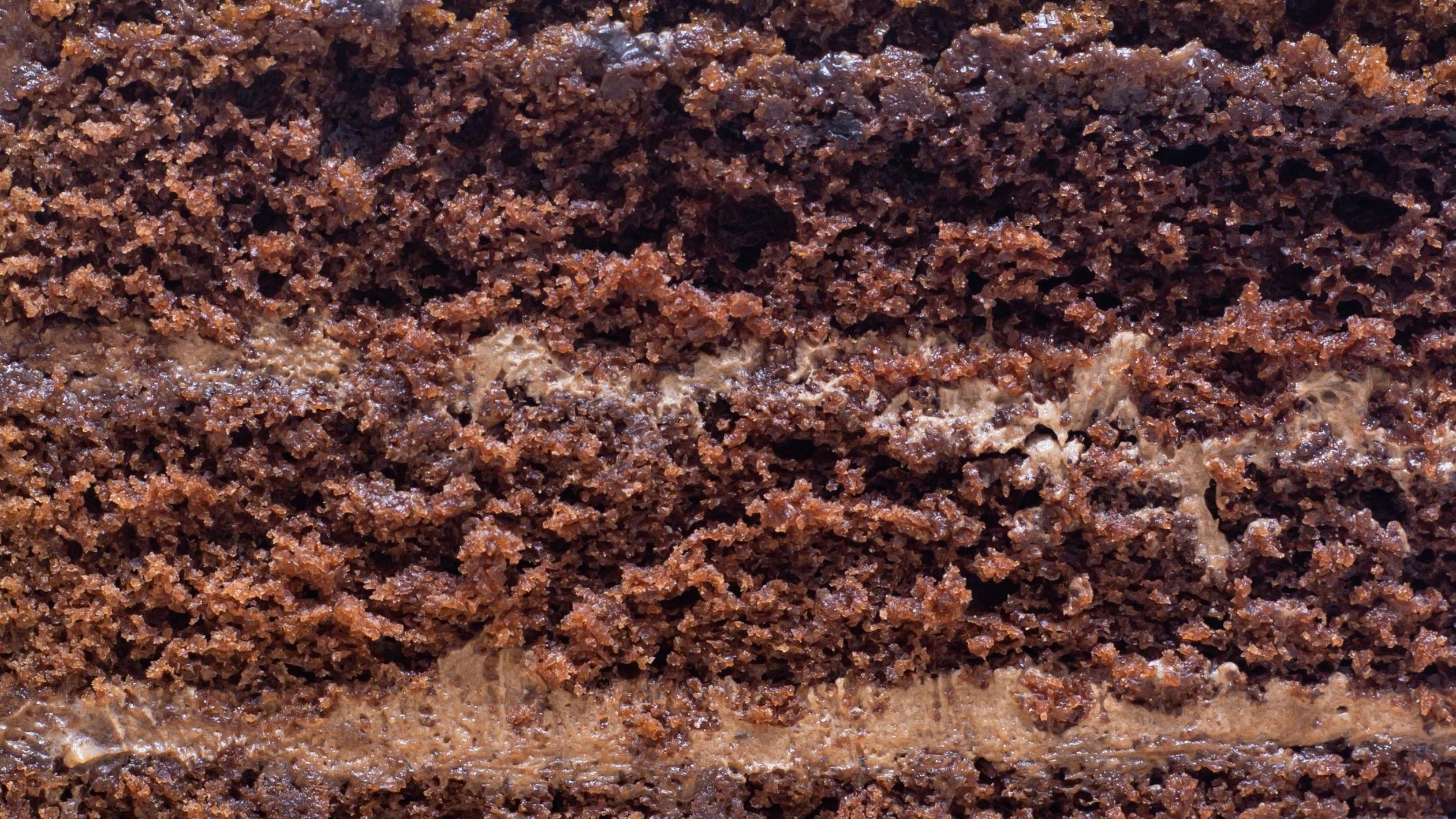 The Texture Of The Divided Chocolate Cake Has Chocolate Cream Sandwiched Between The Middle Of The Close Up Shot
