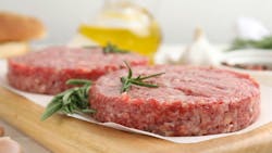 Raw hamburger patties with rosemary on white wooden table, closeup Raw hamburger patties with rosemary on white wooden table, closeup