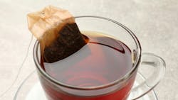 Brewing tea. Glass cup with tea bag on light table Brewing tea. Glass cup with tea bag on light table