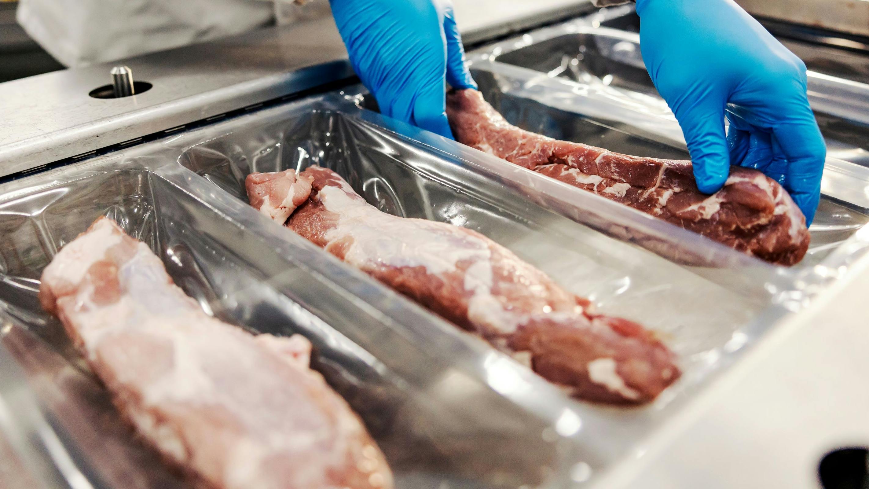 Close Up Of Hands Packing Meat With Vacuum Heat Sealing Machine For Food Pack In Meat Factory