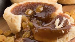 a butter tart on a wooden board showing the sweet filling and raisins flowing onto the board a butter tart on a wooden board showing the sweet filling and raisins flowing onto the board