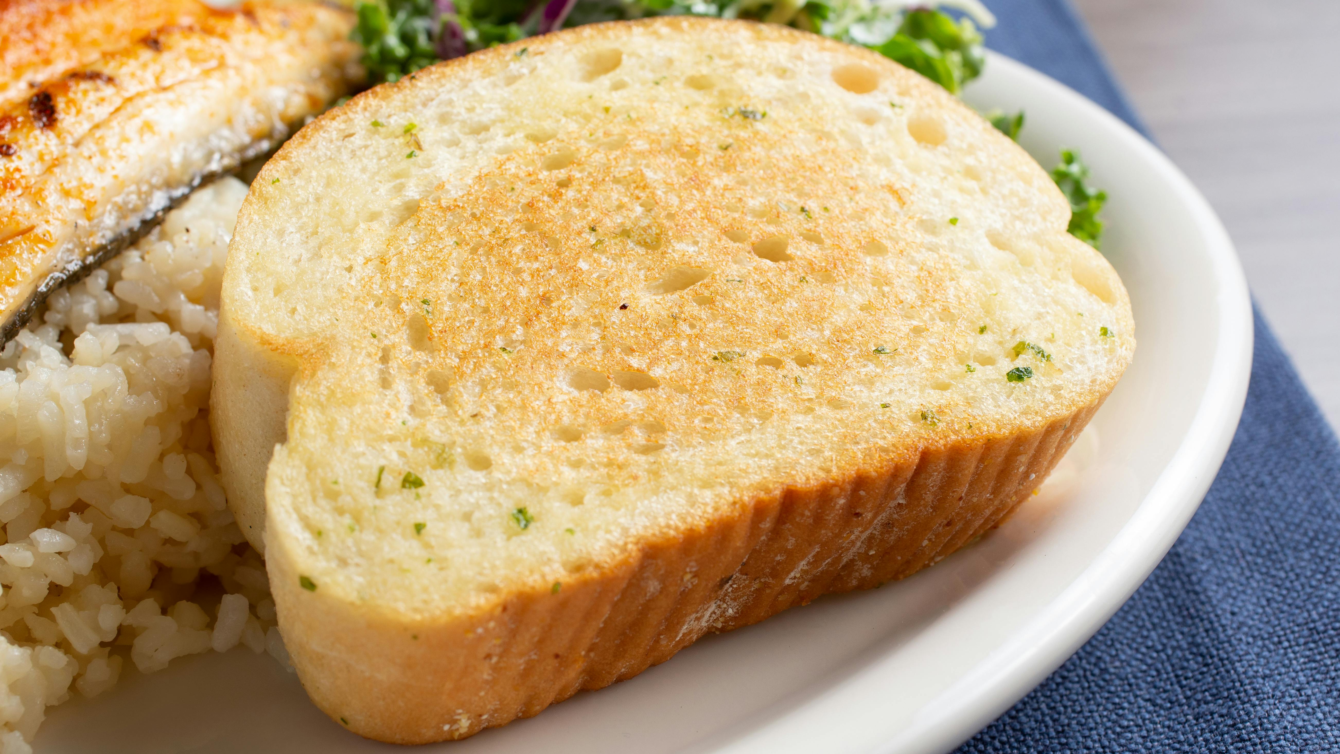 thick slice of garlic toast, part of a seafood entree, in a restaurant or kitchen setting