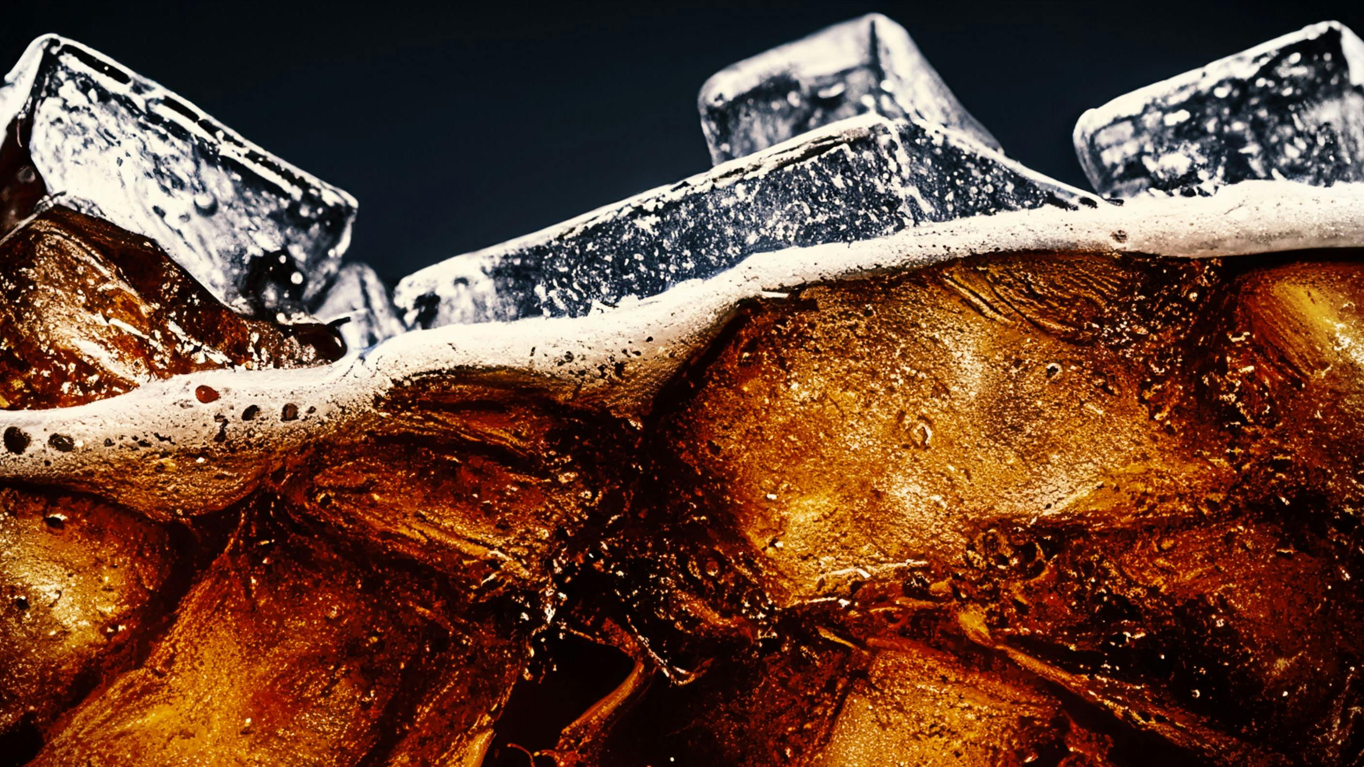 Cola with Ice. Close up of the ice cubes in cola water. Texture of carbonate drink with bubbles in glass.