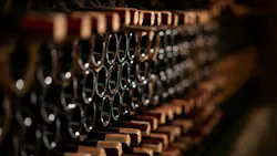 Row of wine bottles on a wooden shelf in a wine cellar Row of wine bottles on a wooden shelf in a wine cellar