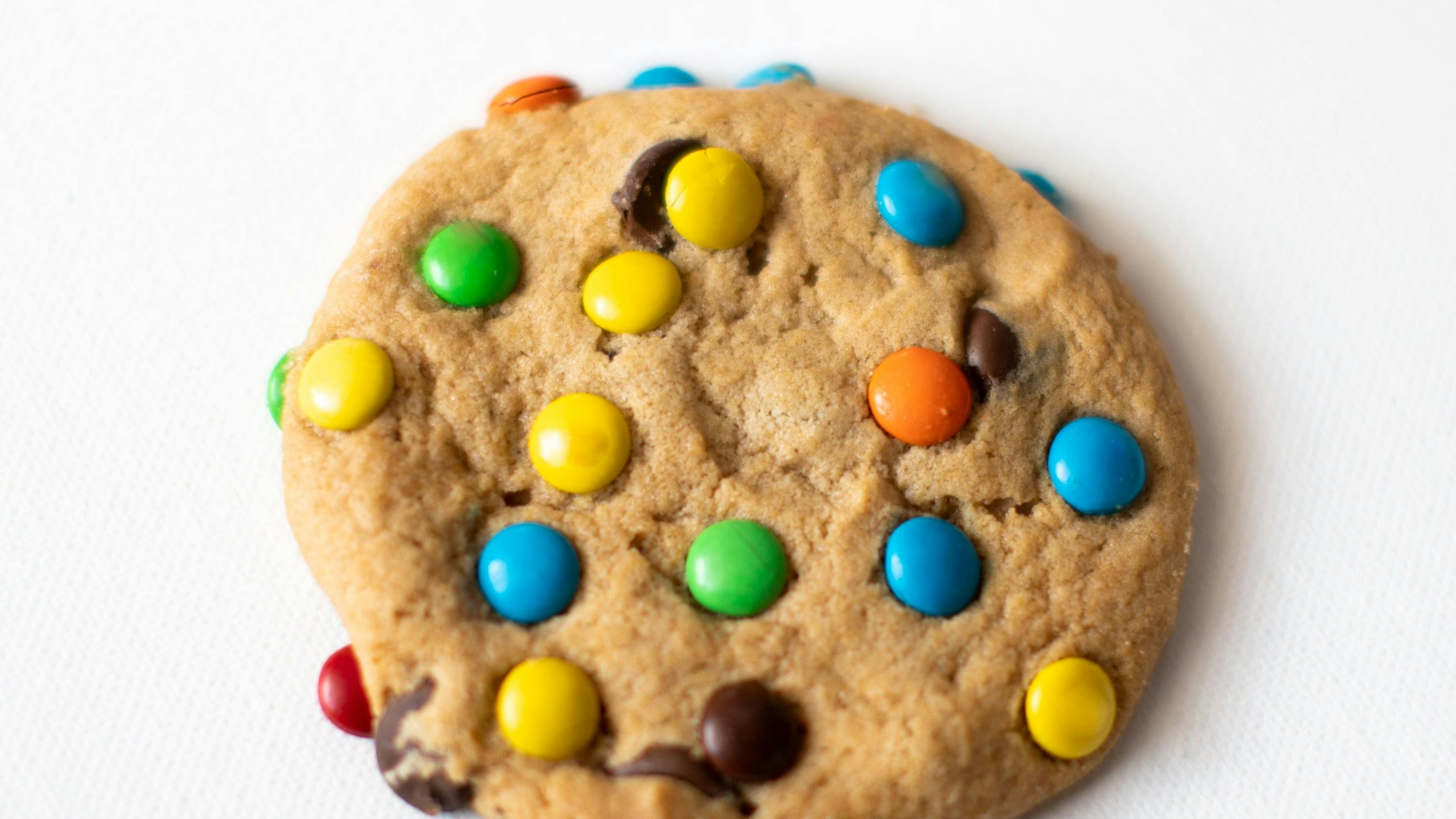 One Single freshly baked Crisp Chocolate Chip Cookie with colorful candy on a white background