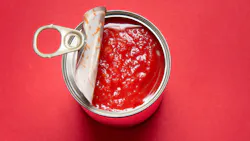 Opened tin can with canned tomatoes, on red background