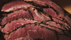 Appetizing pastrami on a kraft paper. Corned beef meat slices by sunset light. Appetizing pastrami on a kraft paper. Corned beef meat slices by sunset light.