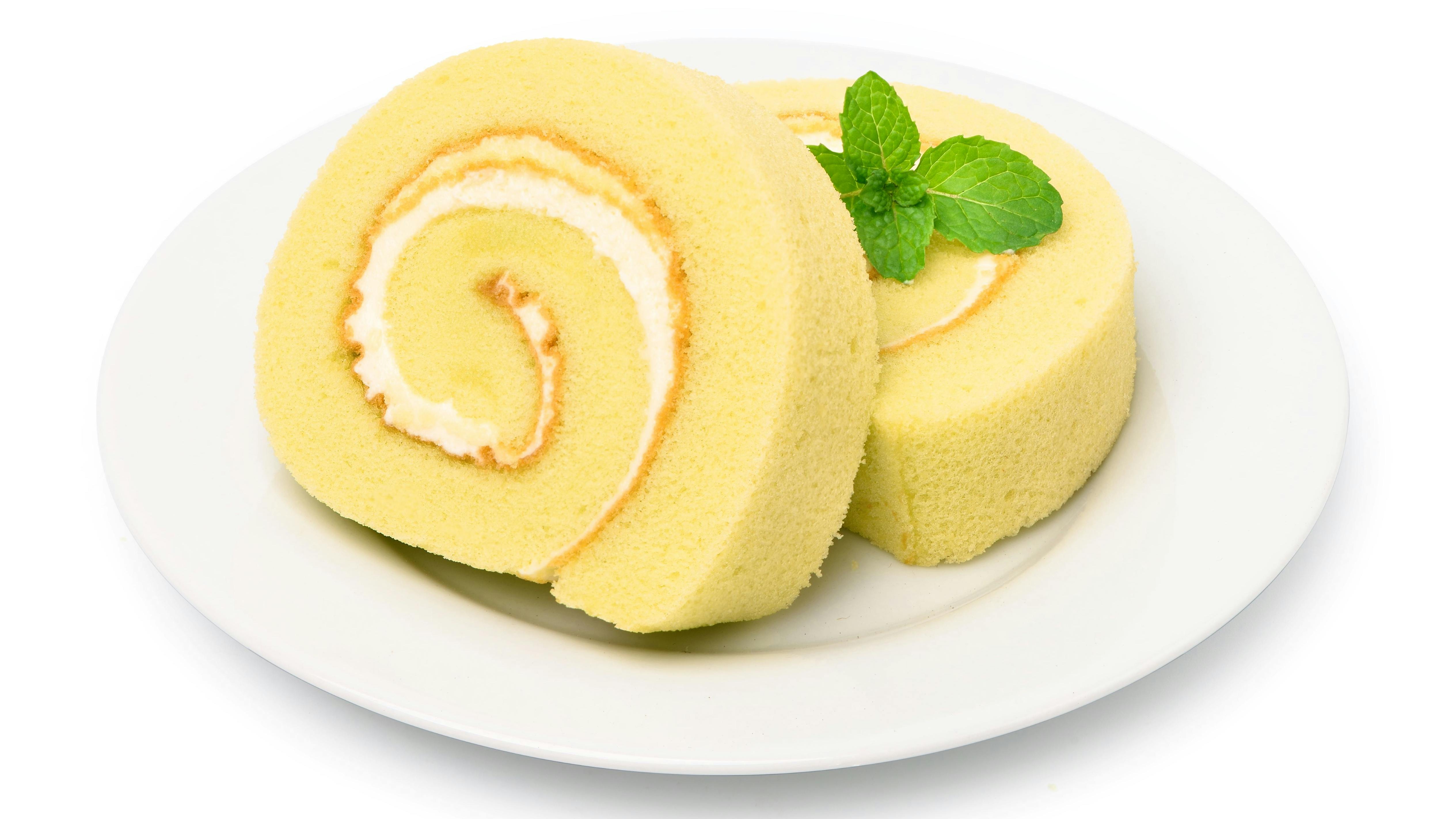 Sponge cake roll slices in white plate with mint leaf isolated on white background.