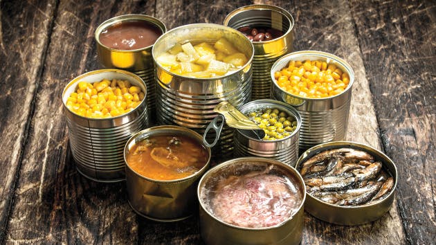 Various canned vegetables, meat, fish and fruits in tin cans.