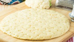 Close up of cauliflower pizza crust on a cutting board Close up of cauliflower pizza crust on a cutting board