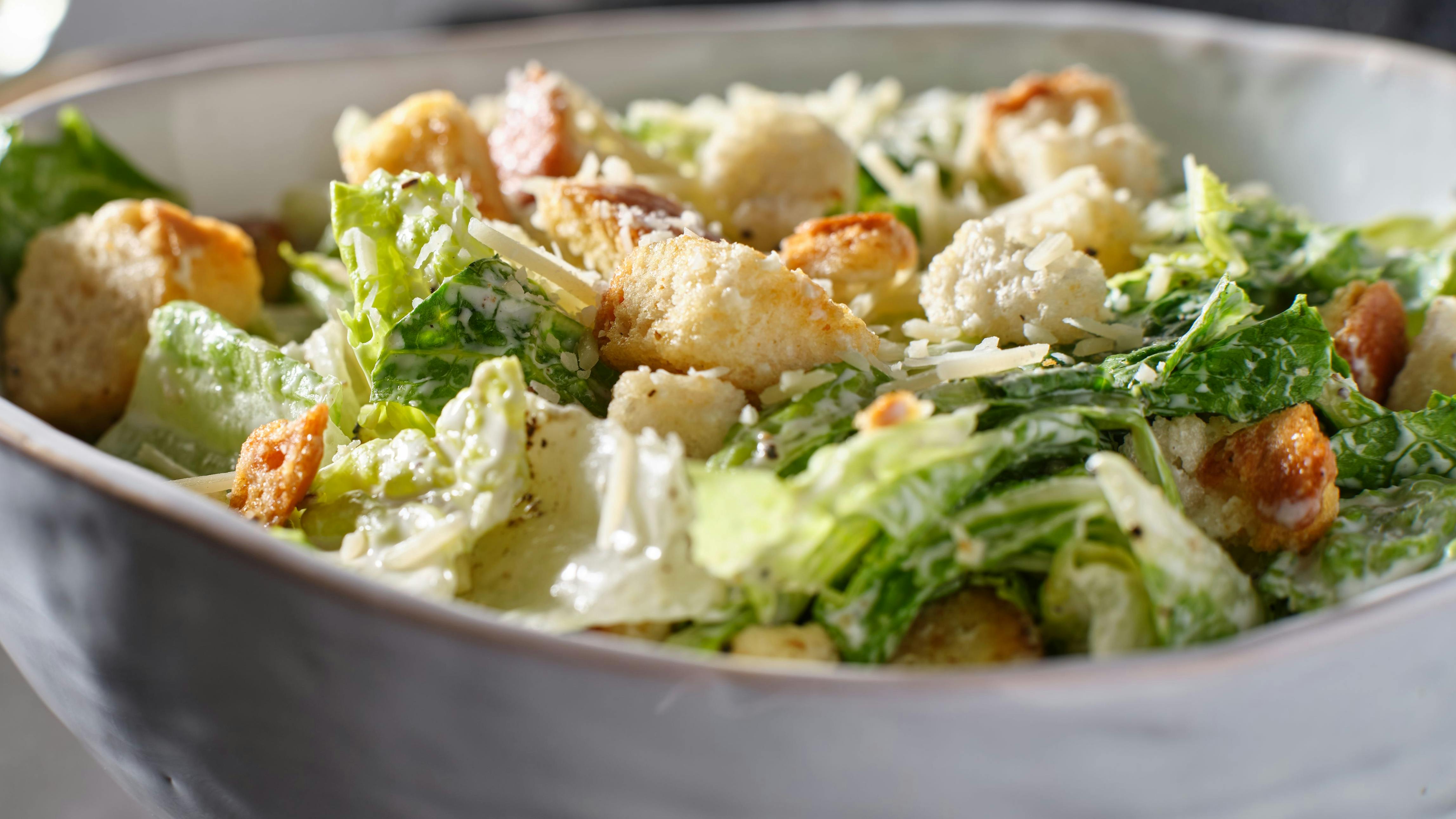 fresh caesar salad with croutons and parmasan cheese in bowl