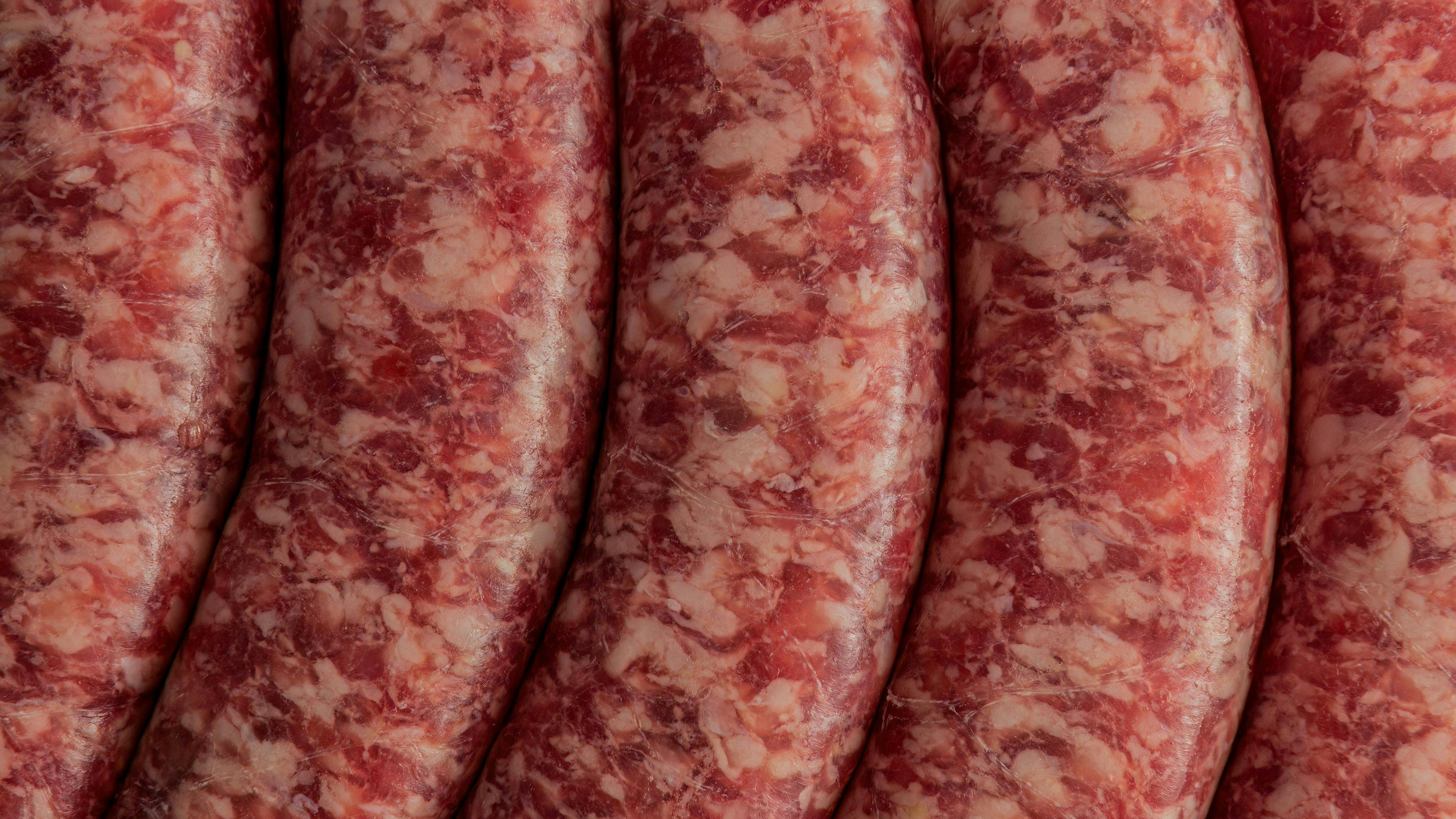 Tight macro shot of fresh Italian sausages, showcasing their marbled appearance and smooth casing