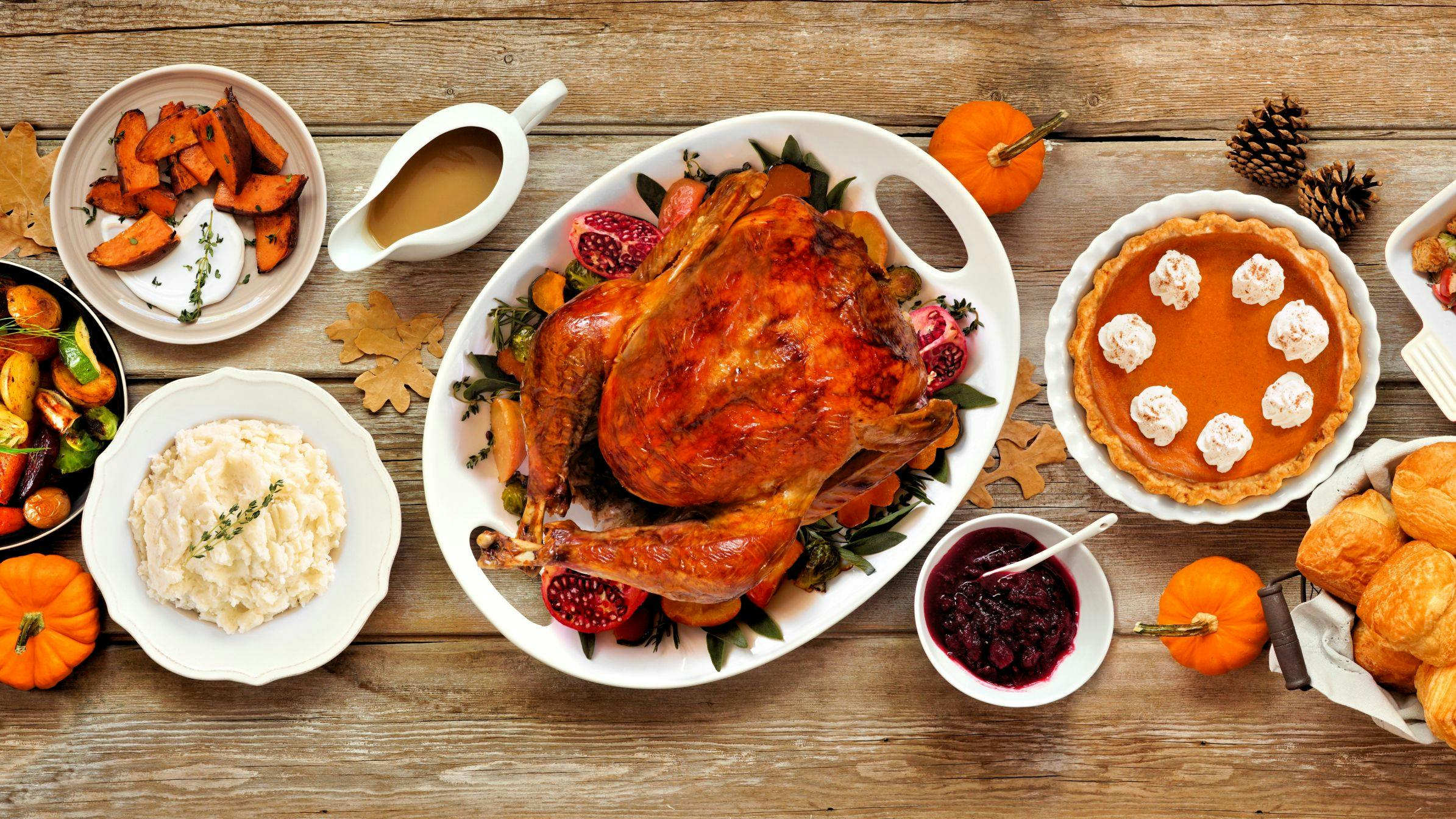 Thanksgiving turkey dinner. Above view table scene on a rustic wood banner background. Turkey, mashed potatoes, stuffing, pumpkin pie and sides.