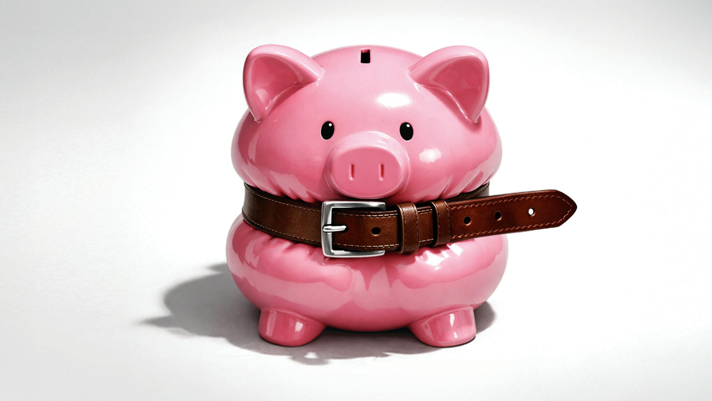 Pink piggy bank squeezed with a belt around the middle