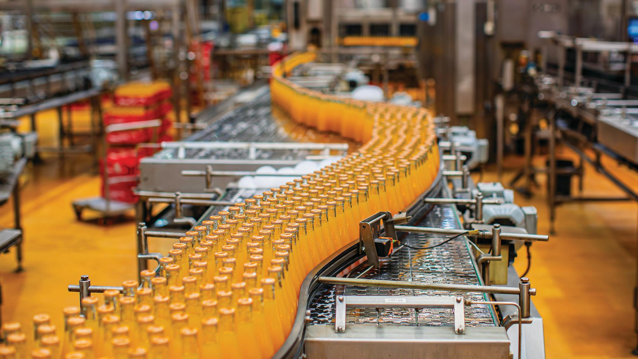 Beverage factory interior. Conveyor flowing with bottles for orange water.