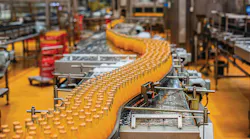 Beverage factory interior. Conveyor flowing with bottles for orange water.
