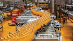 Beverage factory interior. Conveyor flowing with bottles for orange water.